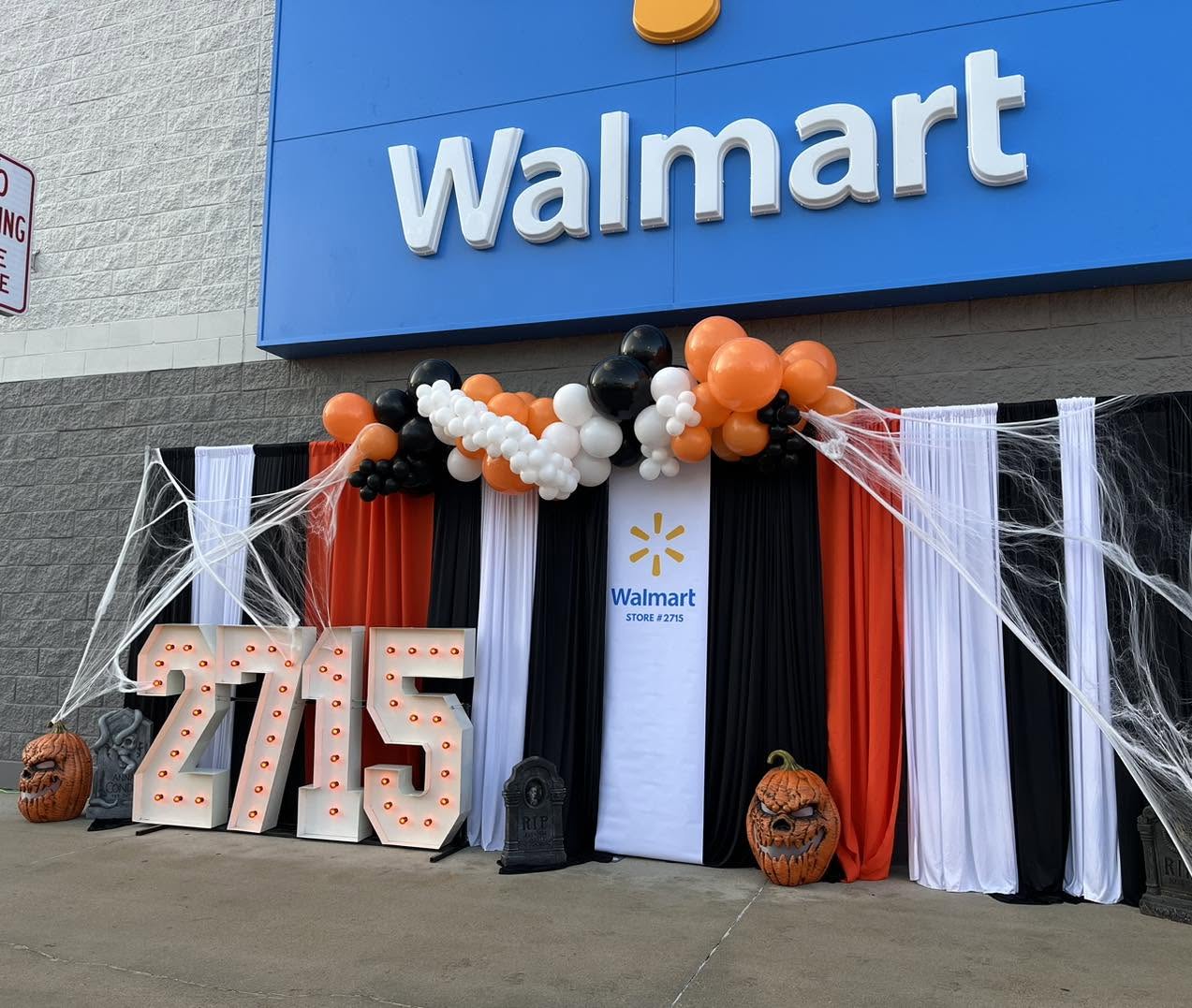 Halloween drape wall with orange, black and white balloon garland and lit marquee numbers